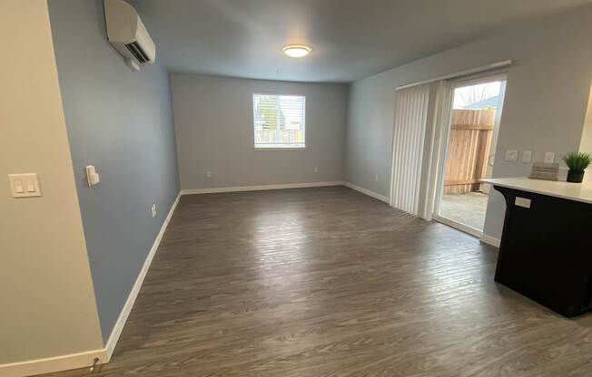 A room with a wooden floor and a window with blinds.