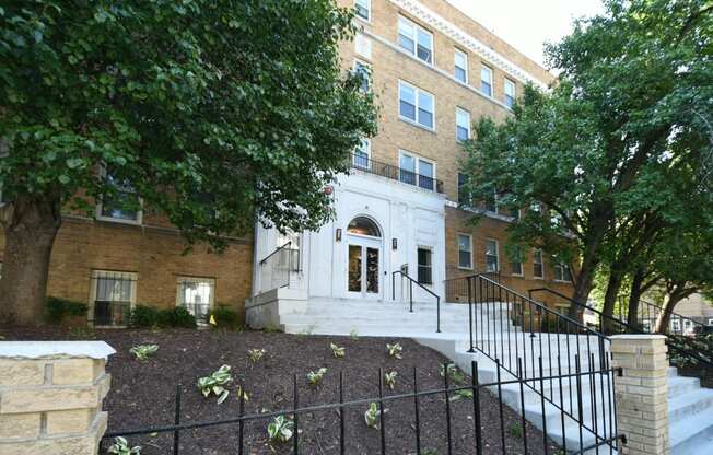 a large brick building with stairs and trees in front of it