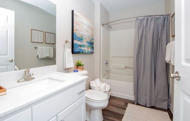 a bathroom with a white sink and toilet next to a bathtub with a shower curtain at The Arden Apartments, Gresham Oregon