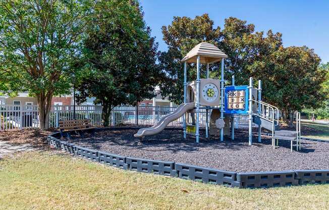 A playground with a slide, a clock tower and a blue sign.