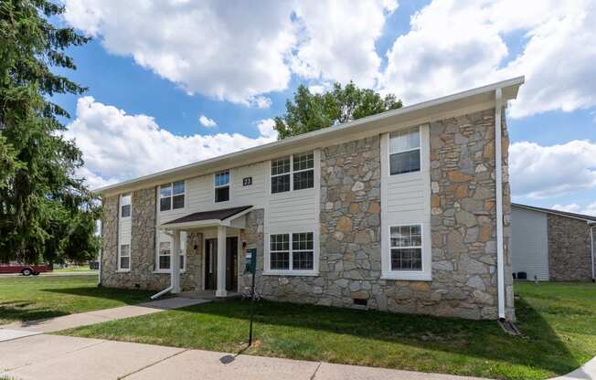 a stone and white building with a sidewalk and grass