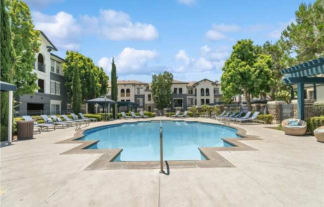 a swimming pool with chaise lounge chairs and trees in the background