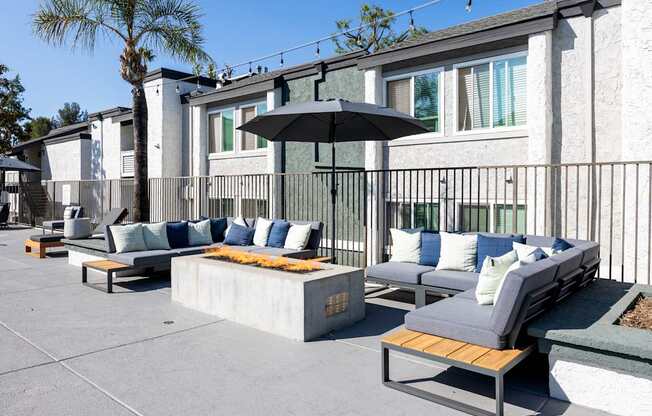 A patio with a black umbrella and grey couches at Verandas Apartments, West Covina, CA, 91791