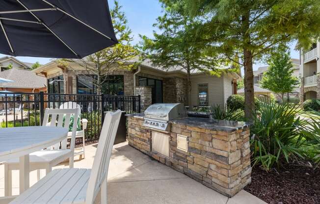 an outdoor kitchen with a grill and a table and chairs