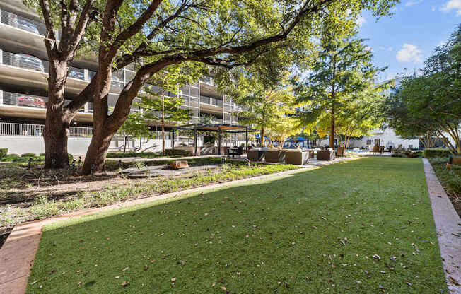 a park with grass and trees in front of a building