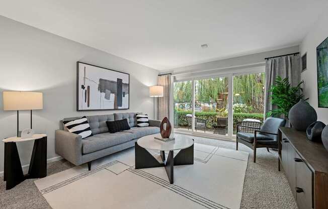 A modern living room with a grey couch, a coffee table, and a painting on the wall.