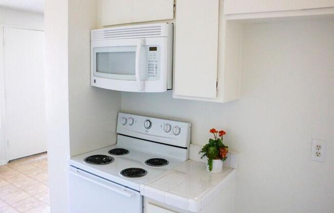 a small kitchen with a white stove and microwave