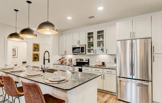 Beautiful kitchen with white cabinetry and an island with a granite countertop inside a Grapevine apartment for rent.