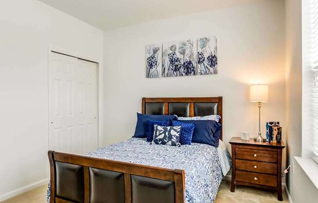 A bedroom with a bed, two chairs, and a nightstand.