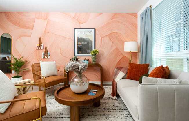 A living room with a white couch, a coffee table, and a pink wallpaper.