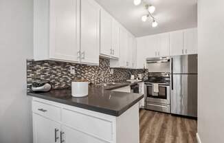 A kitchen with white cabinets and a black countertop.