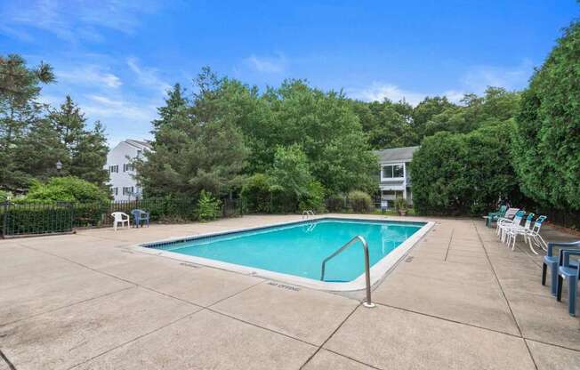 a swimming pool with chairs and a fence around it