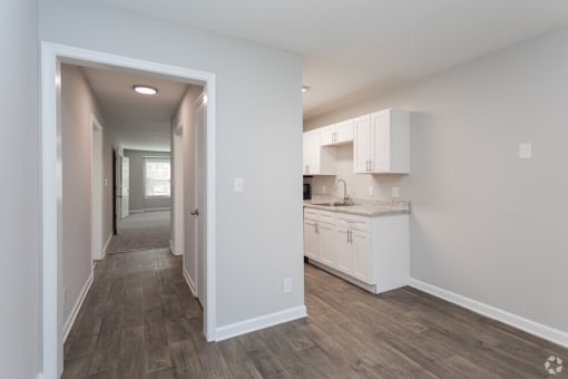 a renovated kitchen with white cabinets and a wood floor