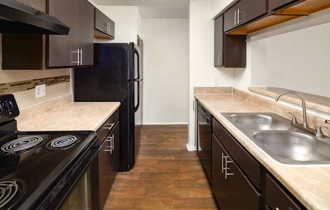 A kitchen with dark wood cabinets and a black refrigerator.