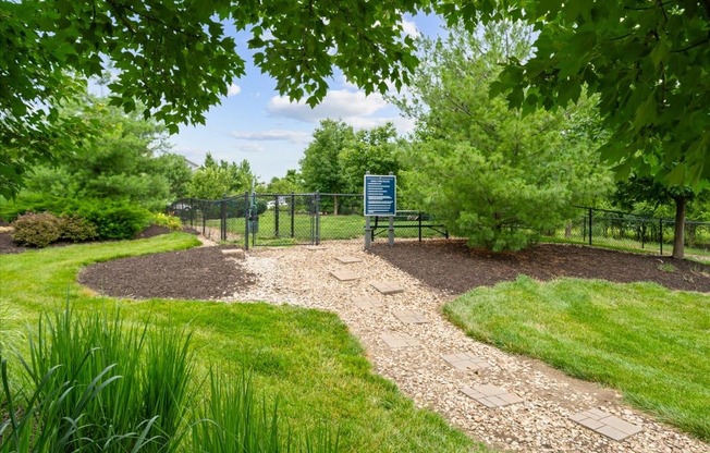 A sign is in a fenced area with a gravel path leading to it.