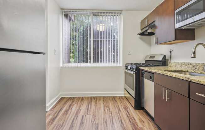 an empty kitchen with stainless steel appliances and a window