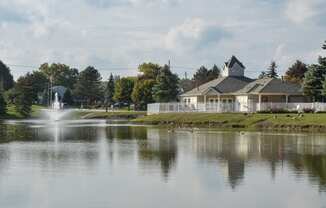 a view of a lake with a fountain and a house