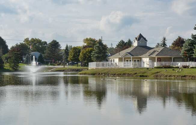 a view of a lake with a fountain and a house