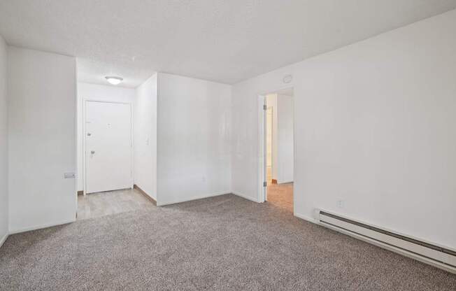 A sparsely furnished room with a carpeted floor and white walls.