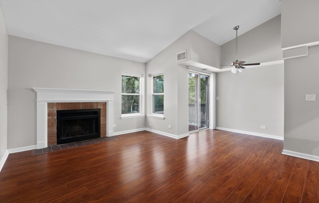 an empty living room with wood floors and a fireplace