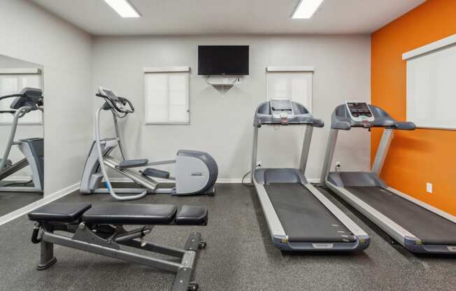 two treadmills and other exercise equipment in a gym with a tv