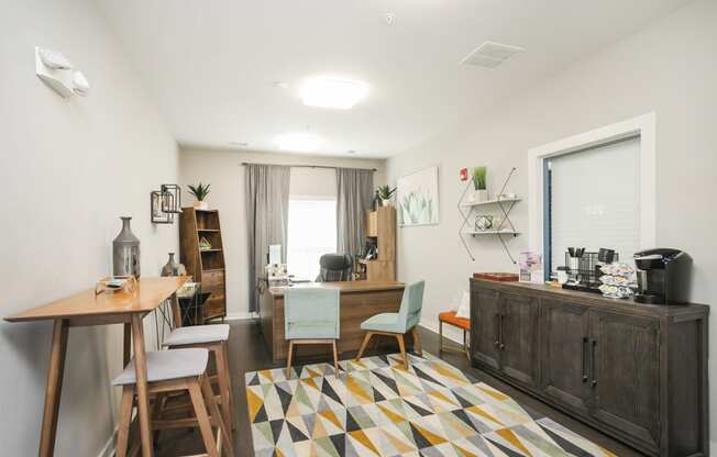 a room with a desk and chairs and a colorful rug