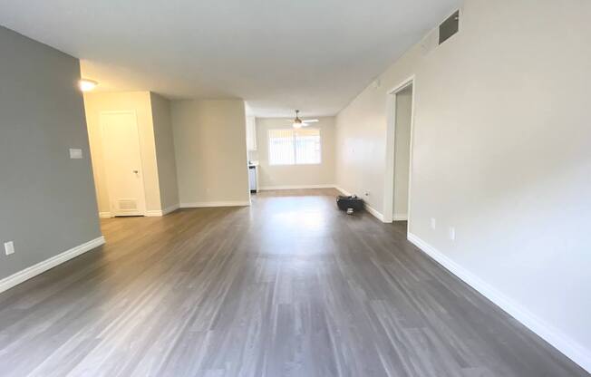 an empty living room with wood floors and white walls