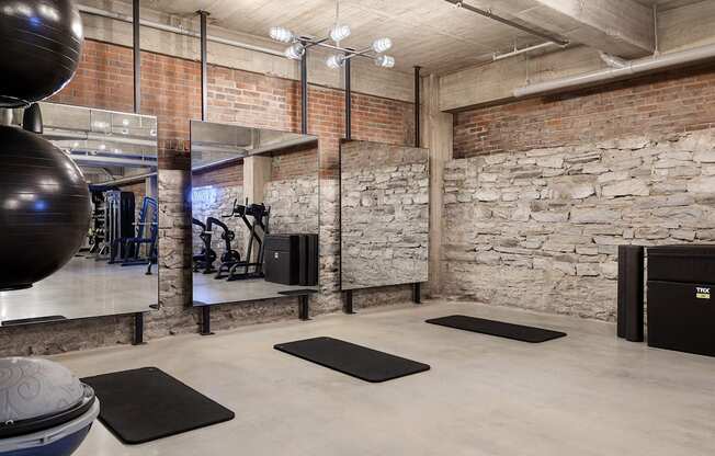the gym has exposed brick walls and a large exercise ball and rugs