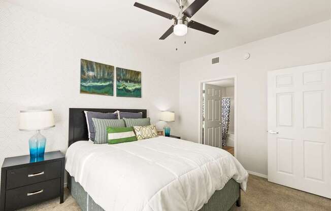 a bedroom with a white bed and a ceiling fan