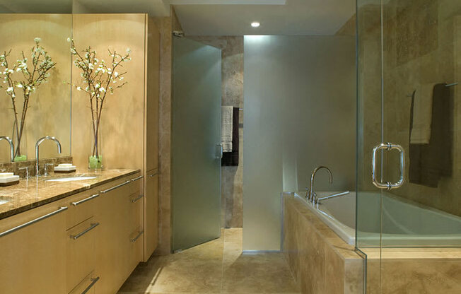 A modern bathroom with a glass shower stall and a sink with a marble countertop.