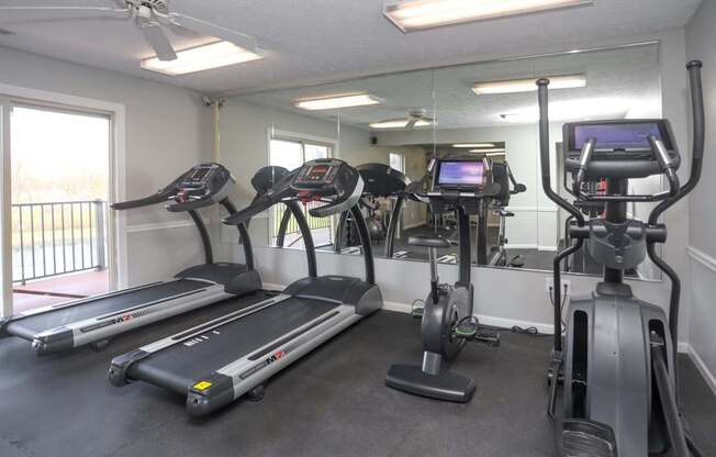 A gym with treadmills, elliptical machines, and a fan.