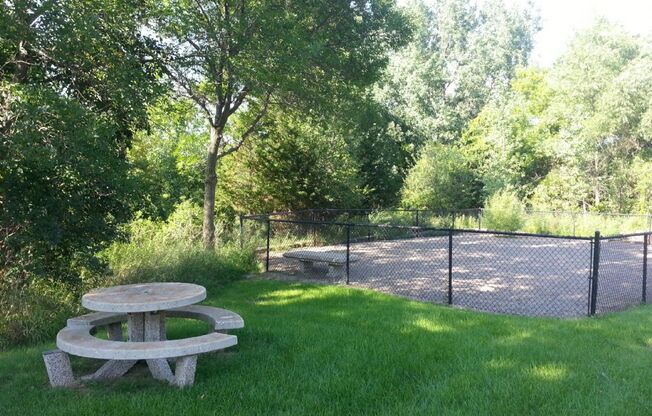 a picnic table in a park next to a fence