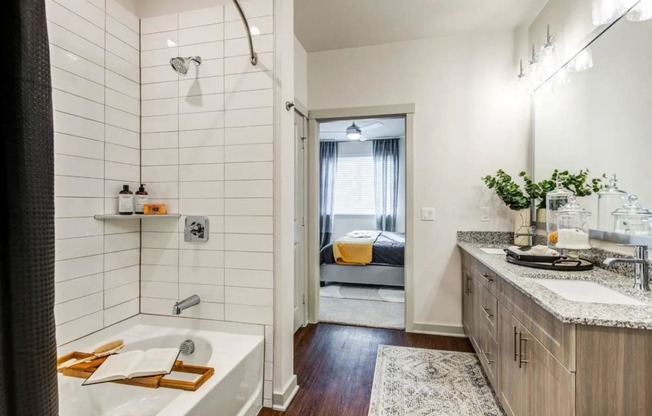 a bathroom with a tub and a sink and a door to a bedroom