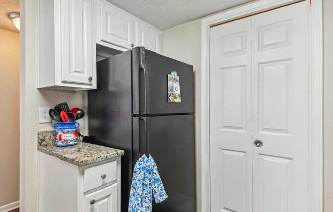 a kitchen with a black refrigerator and white cabinets