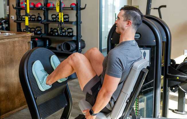 A man is working out on a leg press machine in a gym.