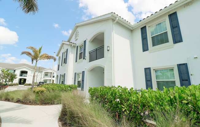 a white building with a palm tree in the background at The Crest at Naples, Naples