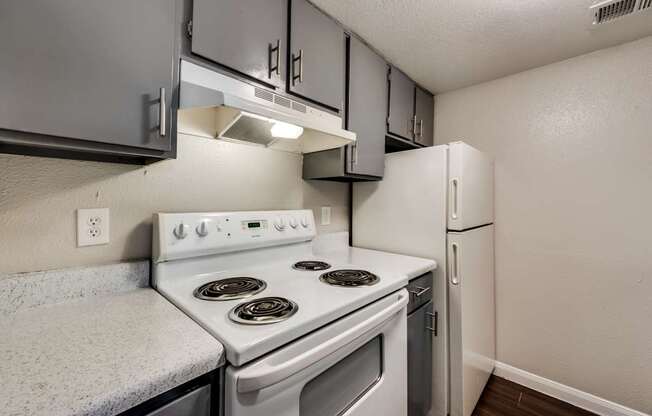 A white stove and oven in a kitchen with a white refrigerator.