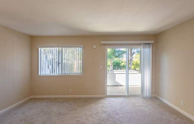 an empty living room with sliding glass doors to a patio