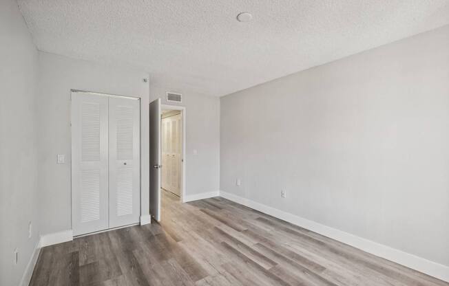 A room with a white door and a wooden floor.
