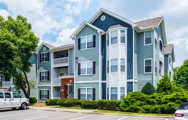 a blue and white apartment building with cars parked outside