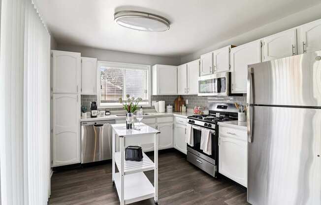 Open-concept kitchen with white cabinets and stainless steel fridge at Ashford at Geneva – pet-friendly apartments in Geneva, IL