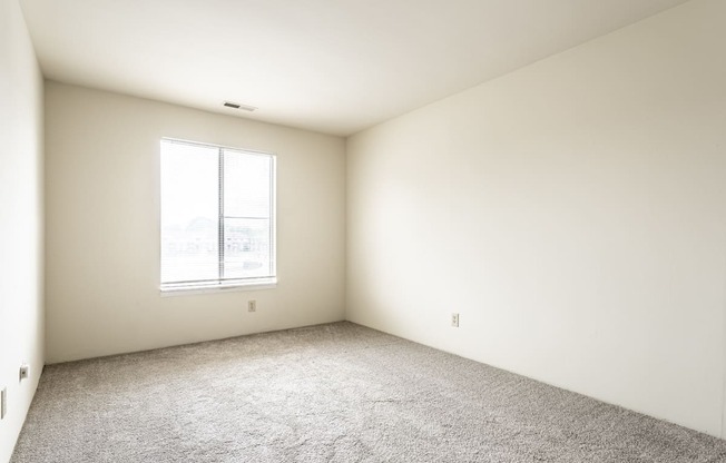 an empty room with carpet and a window