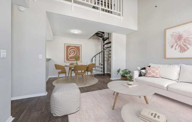 a living room with a white couch and a table and a spiral staircase