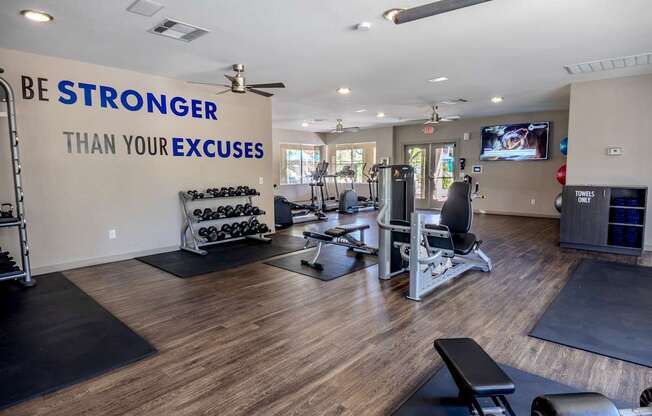 Large gym room with plank flooring, free weights, and aerobic machines