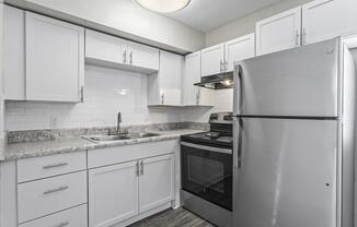 a kitchen with white cabinets and a stainless steel refrigerator