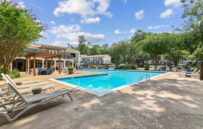 A pool area with sun loungers and a building in the background.