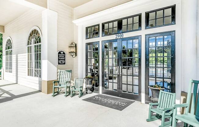 Clubhouse and leasing office exterior entryway with green rocking chairs, welcome mat and covered porch