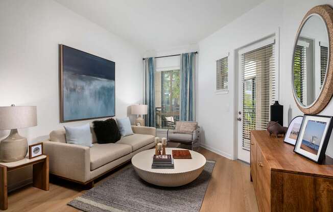 A living room with a beige couch, a coffee table, and a large painting on the wall.
