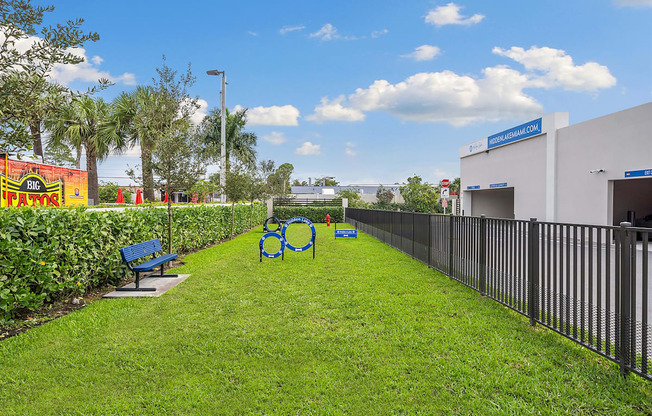 A grassy park with benches and a fence