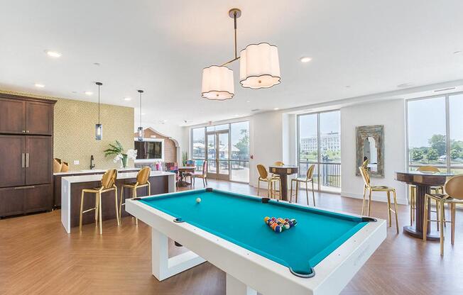 A pool table in a room with a kitchen area in the background.